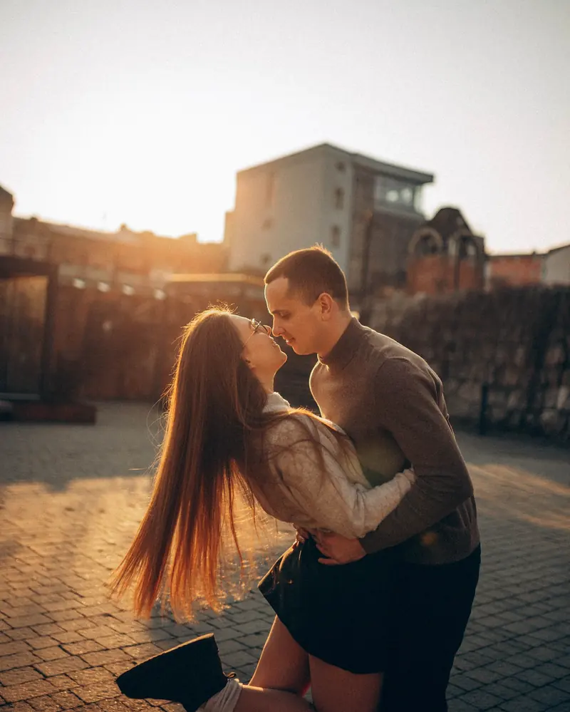 A kiss on an old-town street with the low sun flaring behind the couple.