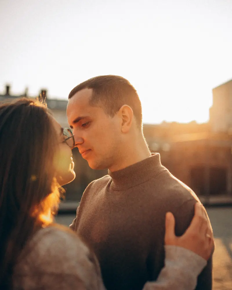 Close-up of a couple touching noses, faces lit by golden evening light.