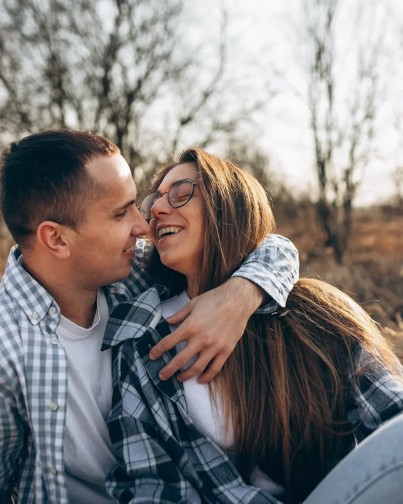 Laughing couple in a tight embrace on a spring meadow.