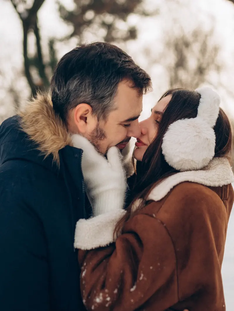 Winter kiss between mum and dad in a snowy Budapest park.