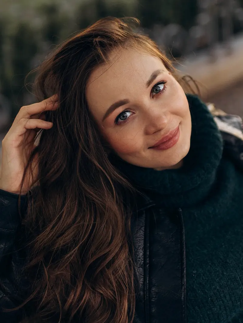 Close-up of the mother-to-be smiling at the camera, hand in her long wavy hair.