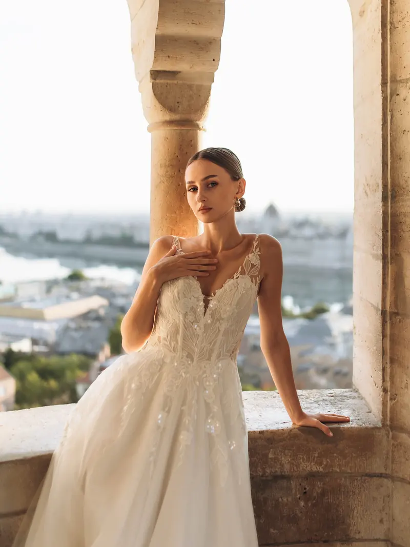 Portrait in a white gown under a Fisherman's Bastion arch, the Danube and Parliament on the horizon.